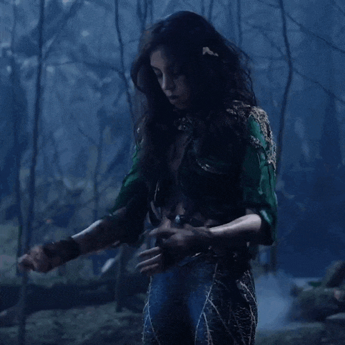 a woman in a green shirt and blue pants is standing in the dark