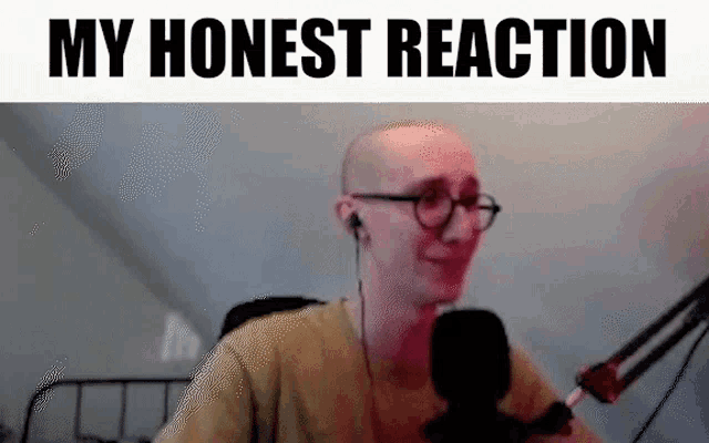 a bald man wearing glasses is sitting in front of a microphone and smiling .