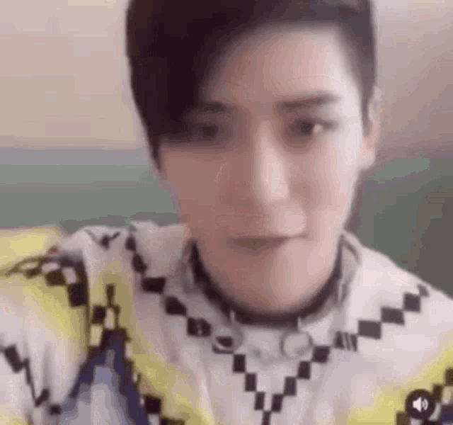 a close up of a person 's face wearing a choker and a checkered shirt .