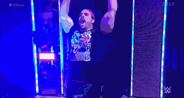 a wrestler with his arms in the air is wearing a black shirt that says 20th anniversary