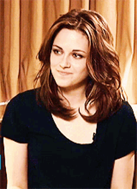 a woman with long brown hair is wearing a black shirt and smiling