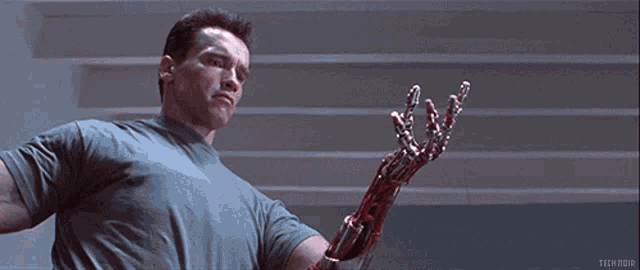 arnold schwarzenegger holds a bloody robotic arm