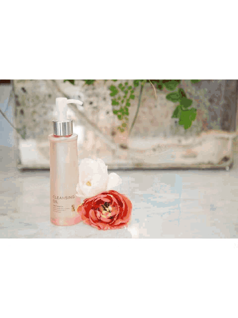 a bottle of inhyunjin perfume sits next to some pink flowers