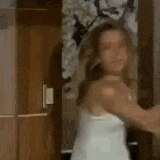 a woman in a white tank top is standing in front of a door in a room .