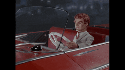 a man in a suit is sitting in a red car