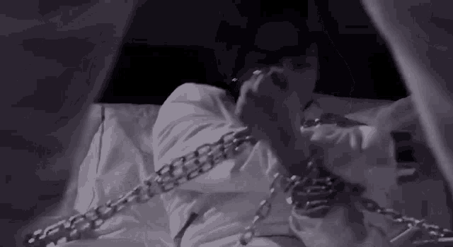 a person is chained to a bed with a cigarette in their mouth .