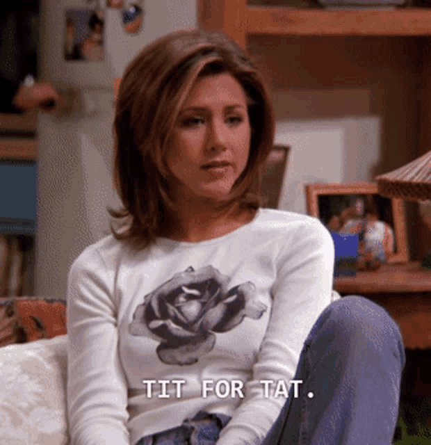 a woman wearing a white shirt with a rose on it says " tit for tat "