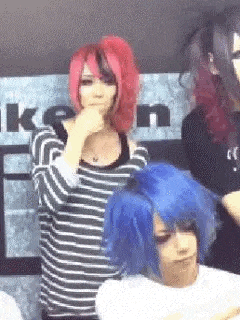 a woman with red and blue hair is standing next to a man with blue hair .