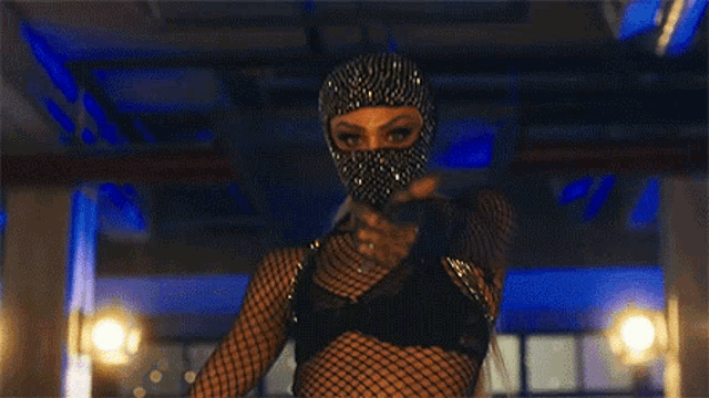 a woman wearing a mask and a fishnet top is dancing