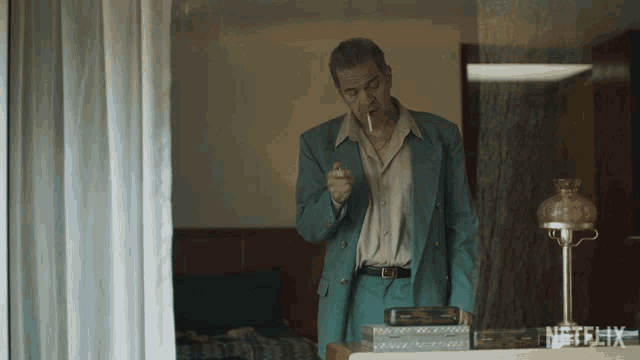 a man in a blue suit is smoking a cigarette in front of a netflix lamp