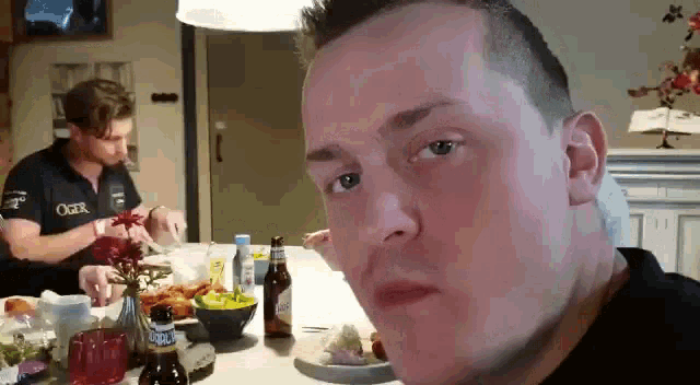 a man sitting at a table with a plate of food and a bottle of beer