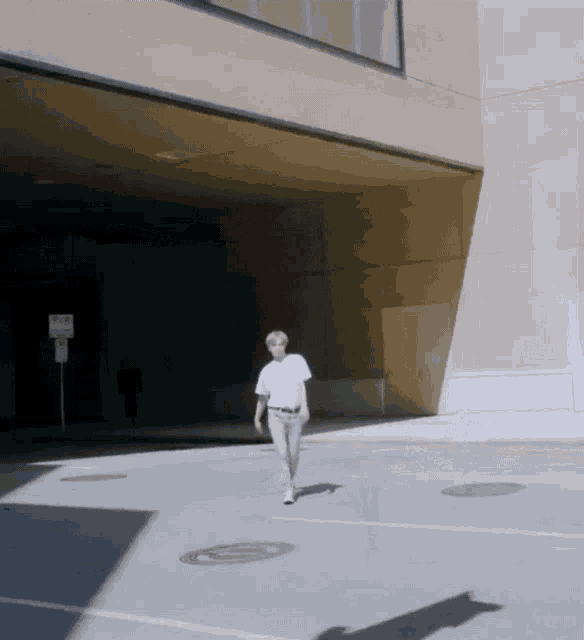 a man in a white shirt walks down a street