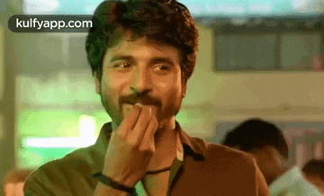 a man with a beard is covering his mouth with his hands .