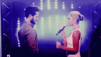 a man and woman are singing into microphones on a stage