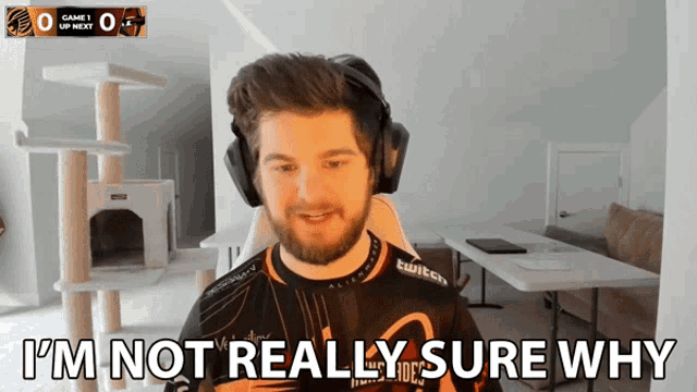a man wearing headphones says " i 'm not really sure why " in front of a cat tree