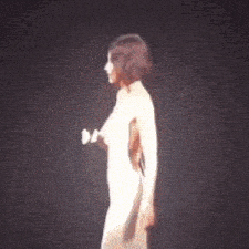 a woman in a white dress is singing into a microphone on stage .
