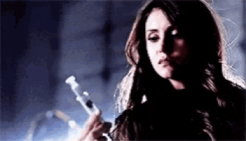 a woman is holding a syringe in her hand and looking at it .