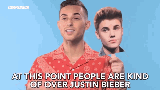 a man holding a picture of justin bieber with the caption at this point people are kind of over justin bieber