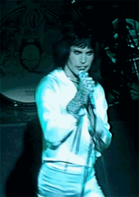 a man singing into a microphone in front of a drum set