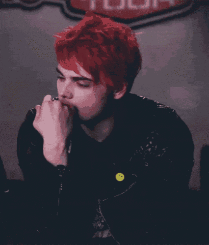 a man with red hair and a yellow smiley face pin on his jacket