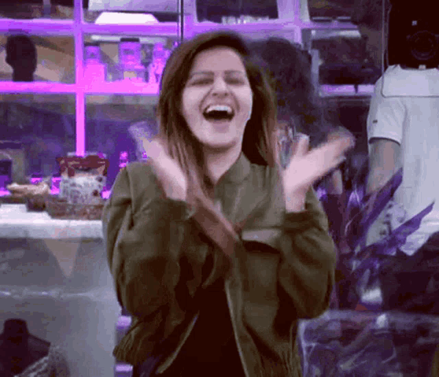 a woman in a green jacket is laughing with her arms in the air