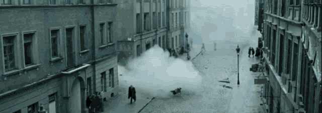 a group of people are walking down a street with smoke coming out of a building .