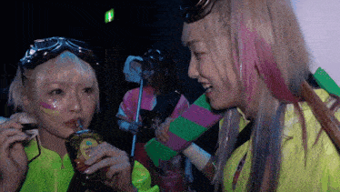 a woman in a neon green jacket drinks from a bottle with a crown logo on it