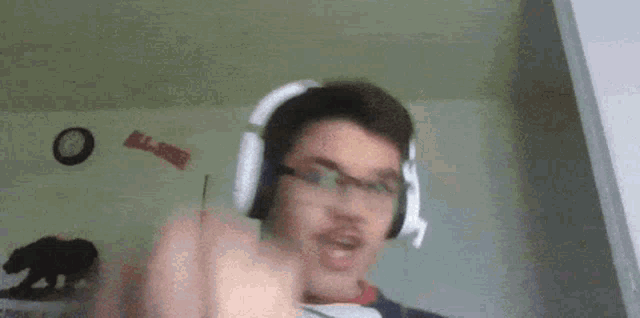 a man wearing headphones is pointing at the camera .