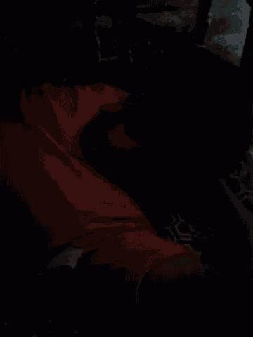 a man in a red shirt is laying on the floor in a dark room