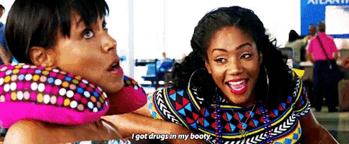 two women are sitting next to each other at an airport talking .