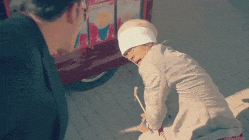 a woman with a bandage on her head is kneeling down in front of a popcorn cart