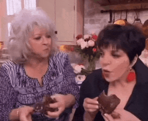 two women are eating ice cream in a kitchen .