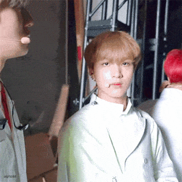 a young man with blonde hair and a microphone in his mouth is standing next to another young man with red hair .