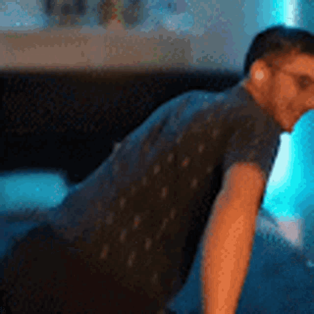 a man in a black shirt is doing push ups on a blue background .