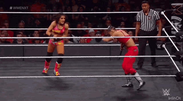 two women are wrestling in a wrestling ring with a referee watching