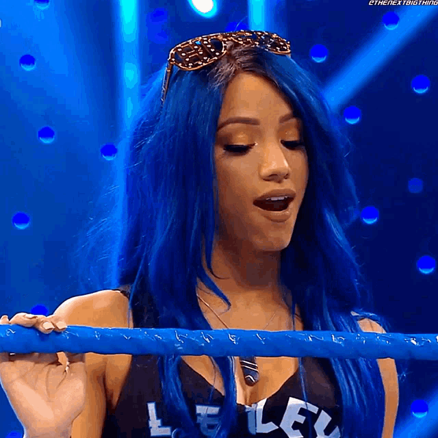 a woman with blue hair is wearing sunglasses and holding a ring