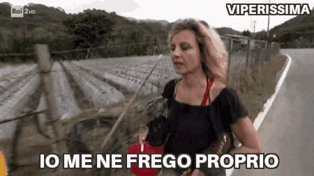 a woman is walking down a road with the words " io me ne frego proprio " on the bottom