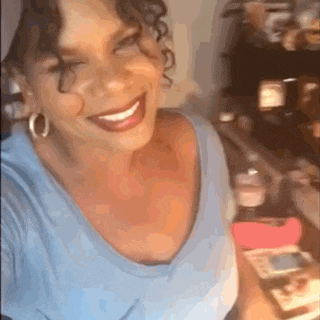 a woman is smiling while taking a selfie in front of a fridge .