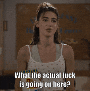 a woman in a white tank top is holding a bag of chips and asking what the actual fuck is going on here