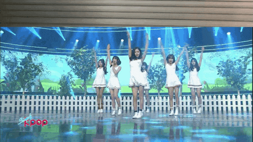 a group of girls are performing on a stage and the word kpop is on the bottom left