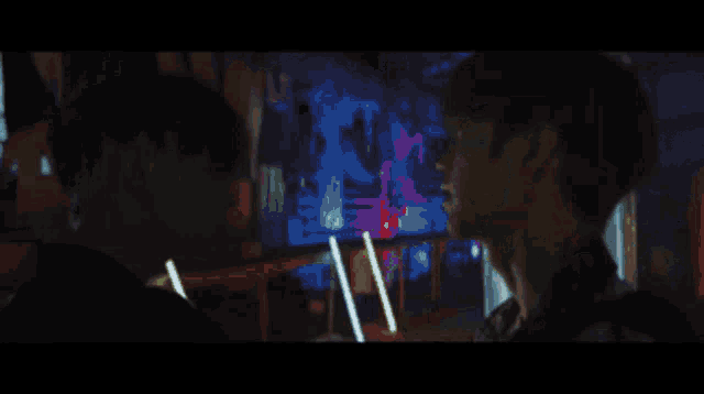 a man and a woman are looking at each other in a dark room with neon lights