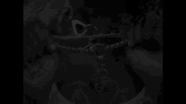 a black and white photo of a woman wearing a necklace with a scorpion pendant on her chest .