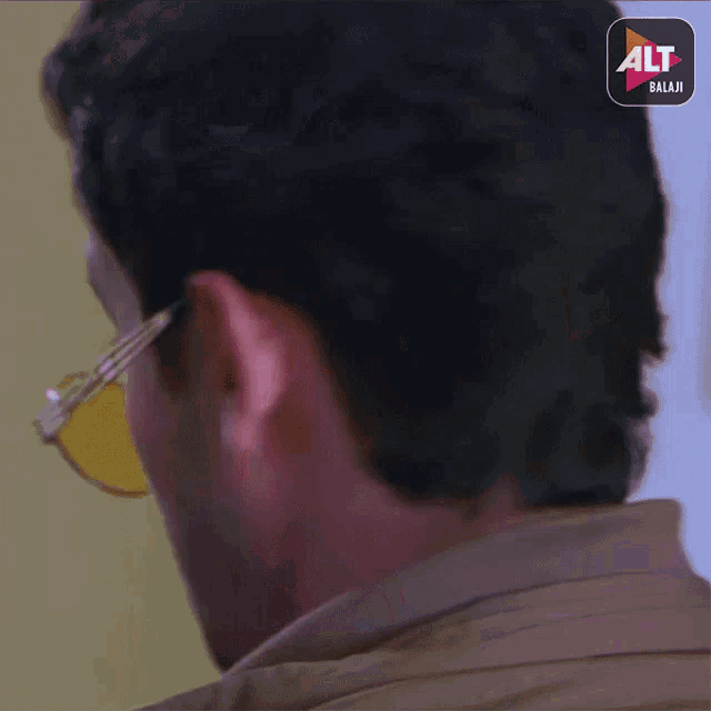 a close up of a man 's ear with a alt balaji logo behind him