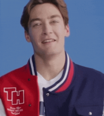 a young man is wearing a red and blue varsity jacket with the letter h on it .
