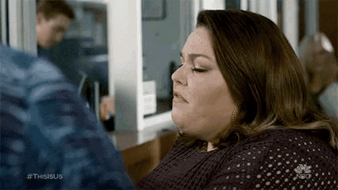 a woman is sitting in front of a refrigerator and looking at a man .