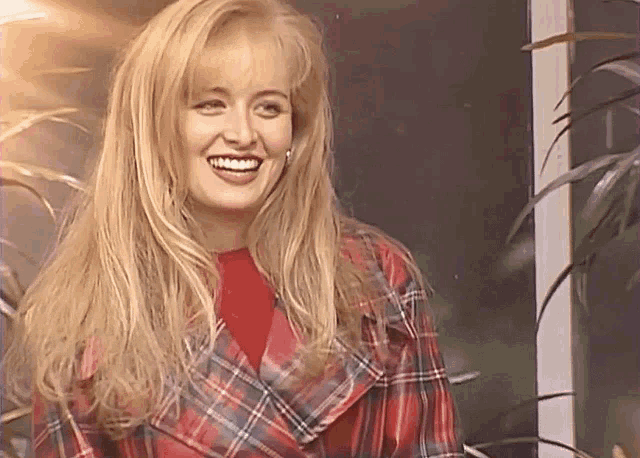 a woman wearing a plaid jacket and red shirt smiles