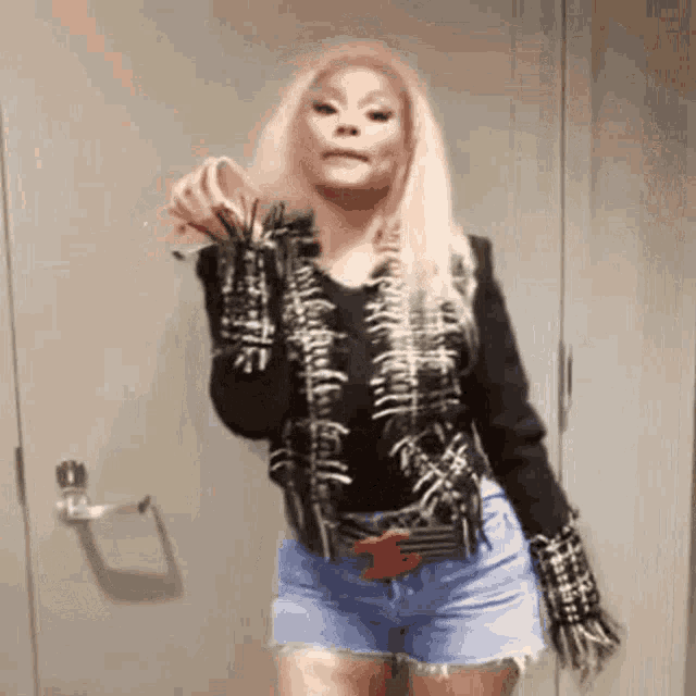 a woman in a black jacket and shorts is standing in a room .