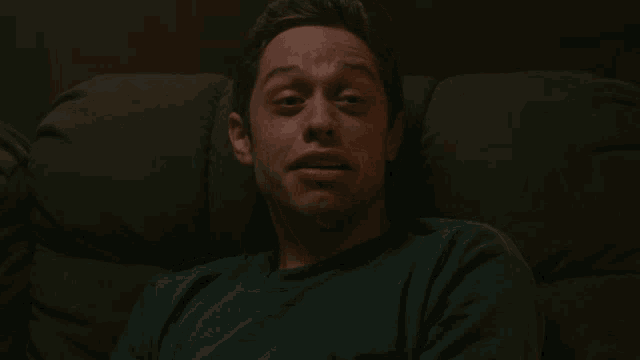 a man with a tattoo on his neck is laying on a couch with his mouth open