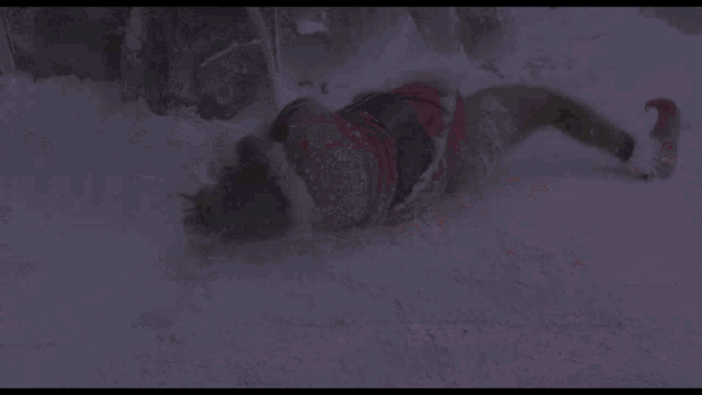 a person in a santa suit is laying on the ground in the snow