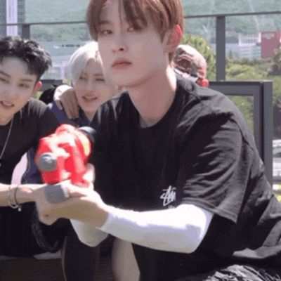 a man in a black stussy shirt holds a red water gun